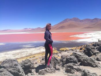 Woman standing on mountain against clear blue sky