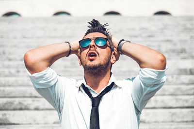 Portrait of young man wearing sunglasses standing against sea