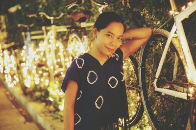 Portrait of happy girl standing against trees at night