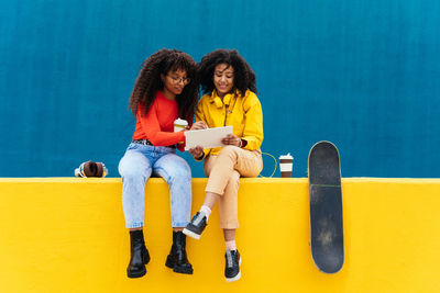 Smiling friends sitting on wall