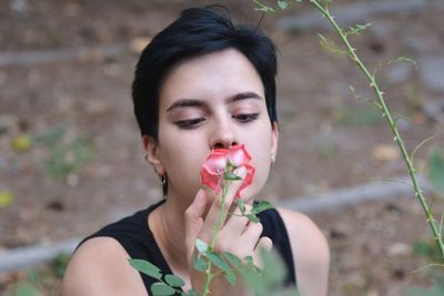 High angle view of young woman smelling rose growing on plant