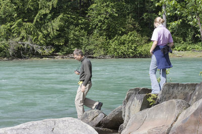 Father and daughter walking on rocks by fraser river