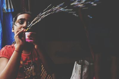 Portrait of woman drinking from glass at night