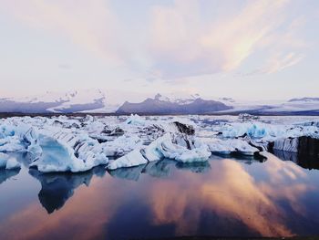 Frozen lake against sky during sunset