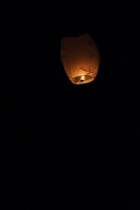 Low angle view of illuminated lantern against black background