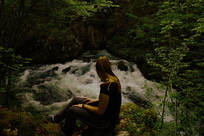 Woman sitting by tree in forest