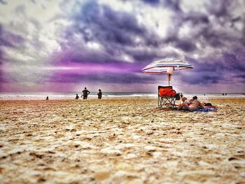 People on beach against sky during sunset