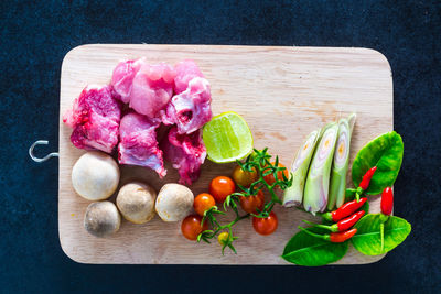 Directly above shot of vegetables and meat on cutting board over table