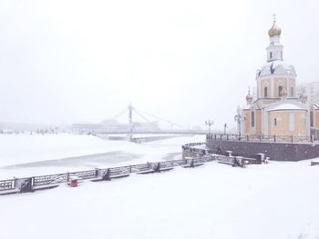 Bridge by buildings against clear sky during winter