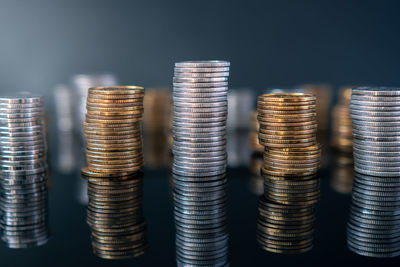 Piles of coins on a black, reflective surface seen from the top. inflation consuming our savings. 