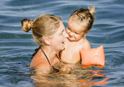 Smiling woman with daughter in sea