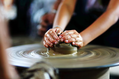 Midsection of woman shaping earthenware on pottery wheel