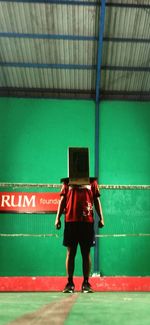 Rear view of woman standing against illuminated wall