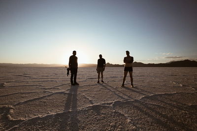 Men standing at bonneville salt flats against sky