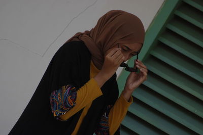 Rear view of woman smoking cigarette against wall