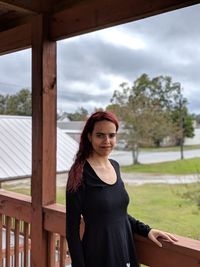 Portrait of smiling young woman standing on porch