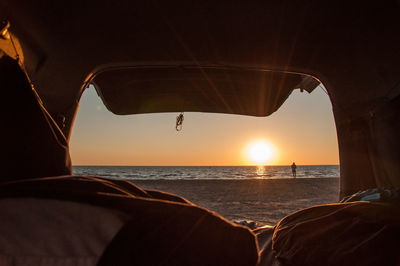 Man paddleboarding in sea against sky on sunny day seen through vehicle