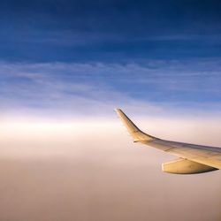 Close-up of airplane wing against cloudy sky