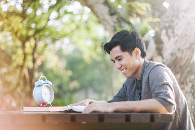 Young man reading book at table in park