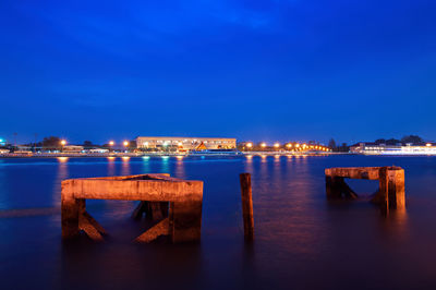 Illuminated pier over sea against blue sky at dusk