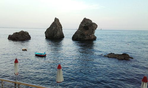 Rocks on sea against clear sky