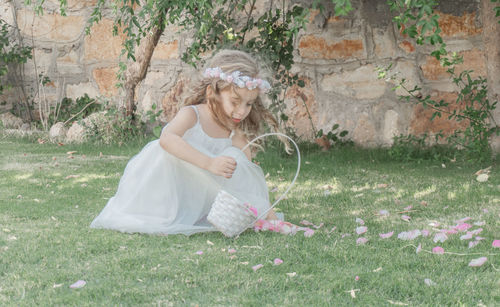 Cute girl collecting petals from grassy field