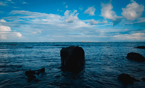 Scenic view of rocks in sea against sky