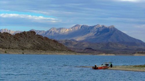 Scenic view of river and mountains against sky