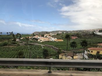 Scenic view of agricultural field by buildings against sky