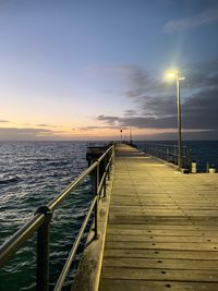 Pier over sea against sky during sunset