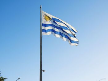 Low angle view of uruguaian flag against clear blue sky