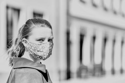 Portrait of woman wearing mask against building