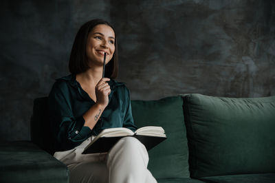 Young woman sitting on sofa at home