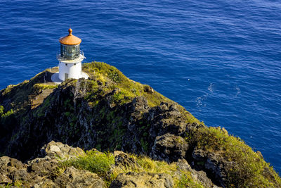 Lighthouse by sea against buildings