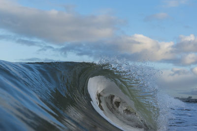 Sea waves splashing on shore against sky