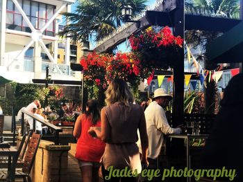 Rear view of people standing by flowers in city