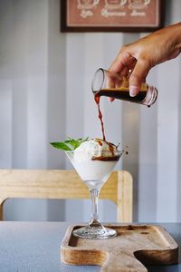 Close-up of hand pouring wine in glass on table