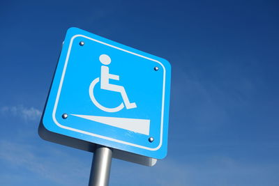 Low angle view of road sign against blue sky