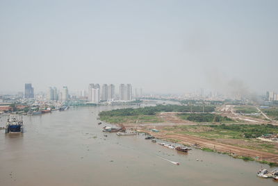Scenic view of river by cityscape against sky