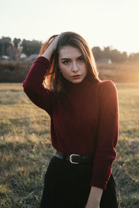 Portrait of beautiful woman standing on field against sky