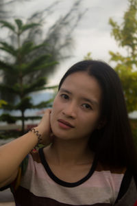 Portrait of smiling young woman against trees