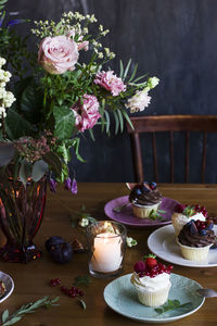 The beautiful festive table with rustic bouquet, cupcakes and space