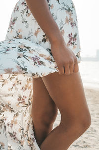 Midsection of woman at beach against sky