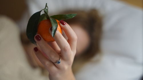 Close-up of woman holding orange fruit