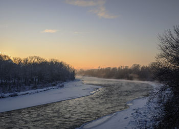 Scenic view of snow covered field against sky at sunset