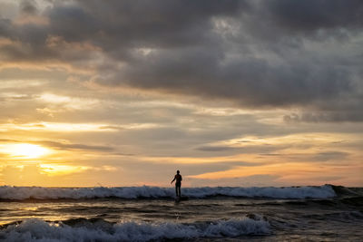 Man standing on beach against sky during sunset