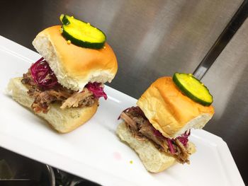 Two pulled pork sliders topped with housemaid pickles