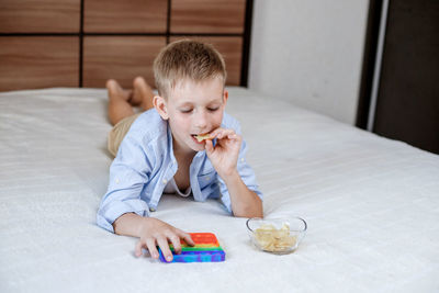 Portrait of boy playing with toy while sitting on bed