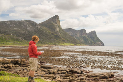 Female tourist reading map while standing at rocky coast in table mountain national park