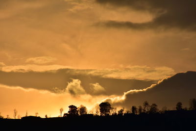 Silhouette landscape against dramatic sky during sunset